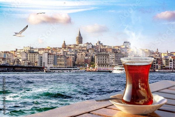 Fototapeta A cup of Turkish tea in a traditional glass against the background of the Golden Horn and the Galata Tower in Istanbul