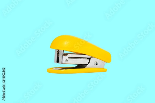 Obraz Yellow-colored stapler closeup on a blue background