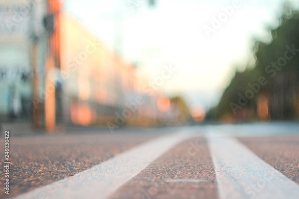 Fototapeta Photo of the road with a double solid strip with a small depth of field, blurred background and variable focus for wallpaper at sunrise