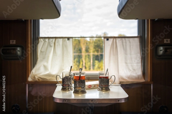 Fototapeta glasses, cups of tea on the table in the train