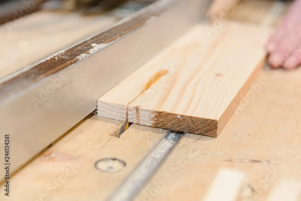 Fototapeta Saw the tree in the home workshop. A man sawing boards.