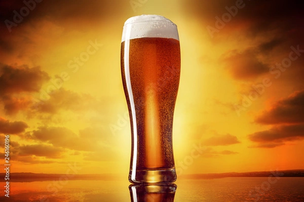 Obraz Szklanka klasycznego piwa india pale IPA na złotym tle zachodzącego słońca nieba.
