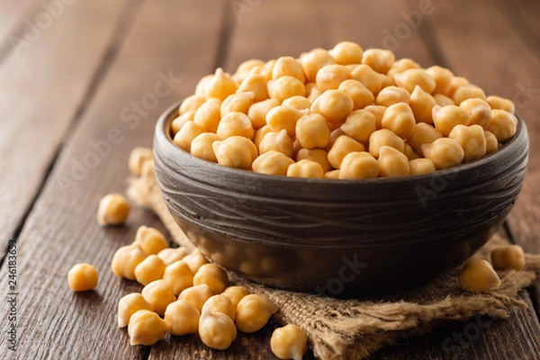 Fototapeta Chickpeas in ceramic bowl on dark wooden rustic table. Selective focus.