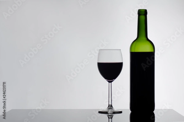 Fototapeta Wine bottle and wine glass on black glossy table white background
