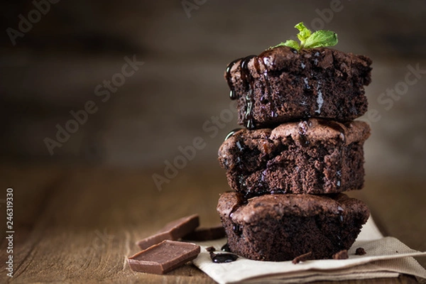 Obraz A stack of chocolate brownies on wooden background with mint leaf on top, homemade bakery and dessert