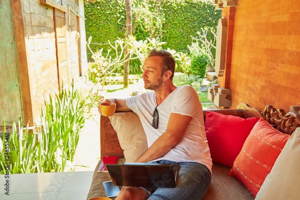 Fototapeta Man with coffee / tea and laptop on a home porch.