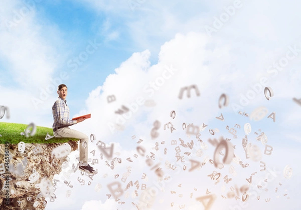 Fototapeta Student guy in suit with book in hands preparing for exam