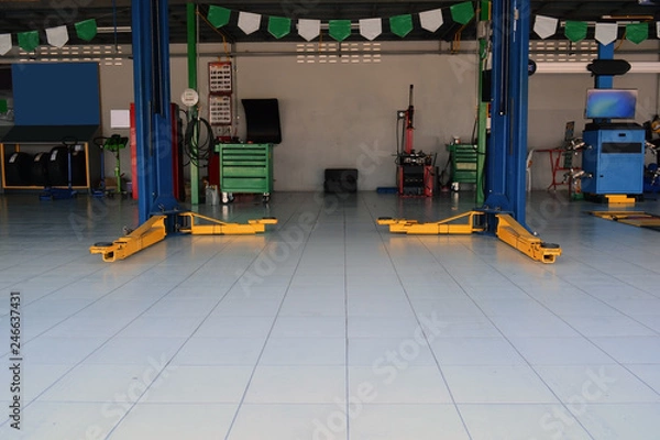 Obraz the yellow lift  hand at the bottom of  the lift post and other  accessory machine  at the car repair shop