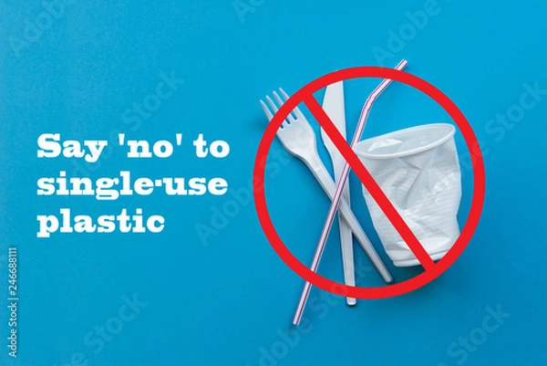 Fototapeta White single-use plastic and plastic drink straws on a blue background. Say no to single use plastic. Environmental, pollution concept.
