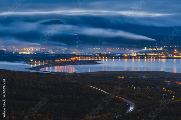 Fototapeta Large industrial plant at night with illumination and heavy smoke from smokestacks. Factory emitting pollution into the air. Extraction of ores and non-ferrous metallurgy. Monchegorsk, Russia