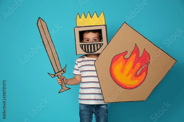 Obraz Śliczne małe dziecko w tekturowej zbroi na kolorowym tle