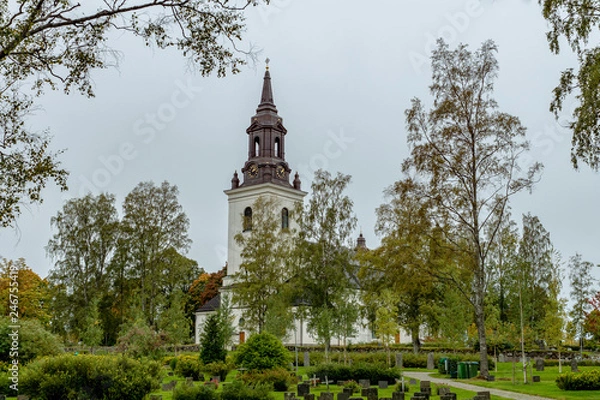 Fototapeta Church in Sweden with colorful autumn trees and a cemetery in front