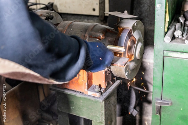 Fototapeta Worker with a grinder machine in a factory