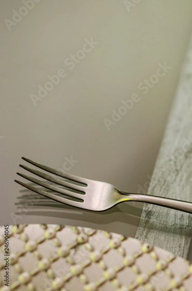 Fototapeta close up of a chrome fork with a silver plate on one side on a transparent glass table