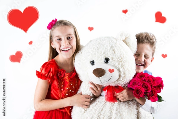 Obraz Pretty little girl and boy  celebrating Saint Valentine's Day and holding red roses bucket  and white bear gift on the white background with red hearts