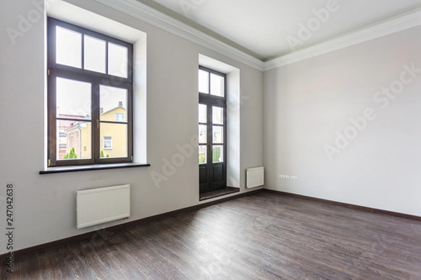 Fototapeta Side view of unfurnished room loft interior with wooden floor, white walls  with bright daylight