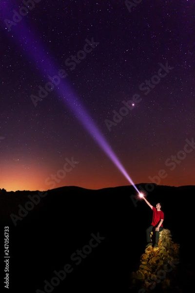 Obraz A man pointing to the sky with a flashlight.
