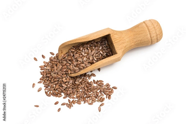 Fototapeta Linseeds or flax seeds on a wooden scoop or spoon seen almost directly from above isolated on white background