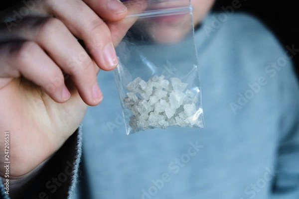Fototapeta hand holds packet with white narcotic - cocaine, meth or another drug