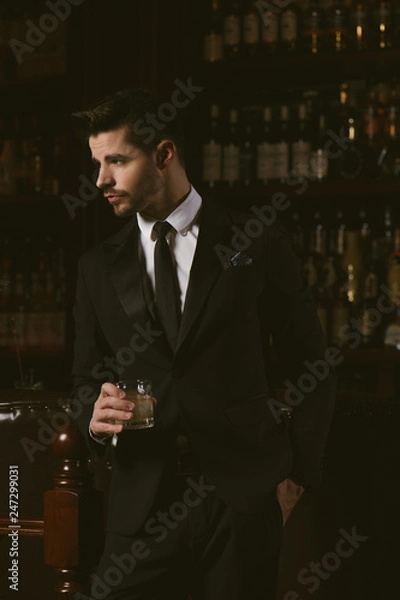 Fototapeta Attractive man wearing black tuxedo in whiskey bar.