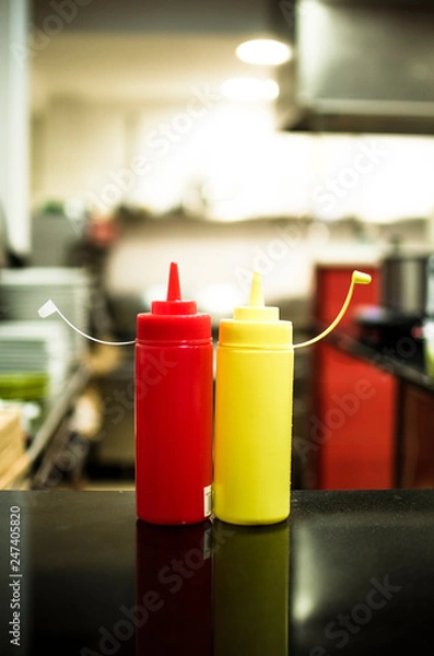 Fototapeta plastic containers for ketchup and mustard sauces together seems that they are waving in the kitchen of a restaurant