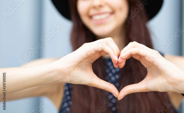 Obraz Strzał zbliżenie wesoła dziewczyna z długimi włosami co kształt serca palcami. Miejsce na tekst