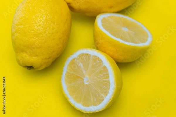 Fototapeta Close-up of cut lemons on yellow cutting board