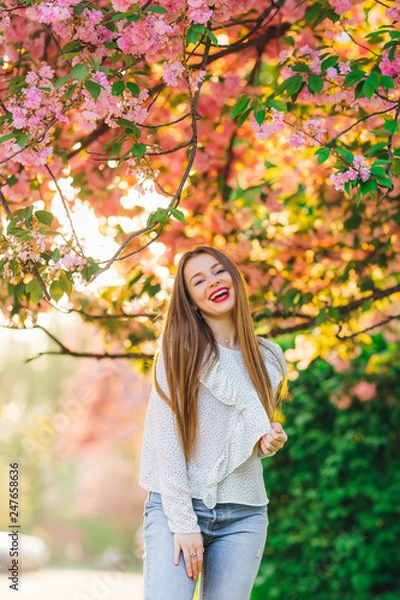 Fototapeta A girl with long hair smiles and looks at the camera lens. over