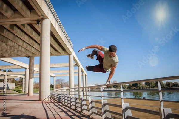 Obraz Afro American fitness man doing exercise, jumping in a park during a blue and sunny day