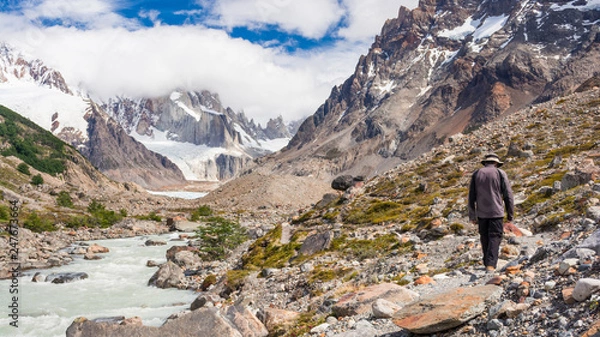 Obraz Young man walking near a river and lagoon Torre with mount Torre and glaciers on the background on a sunny summer day, near campsite De Agostini, in El Chalten, Patagonia Argentina