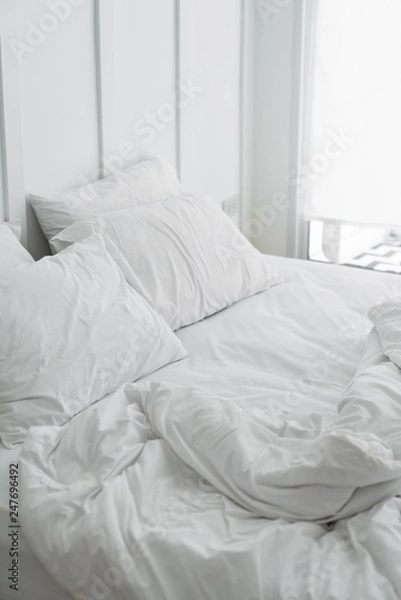 Fototapeta Cozy bedroom setting with two pillows and messy blanket and classic element install on white painted wall / modern classice style / luxury concept / interior