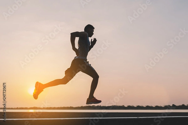 Fototapeta young man runner running on running road in city park