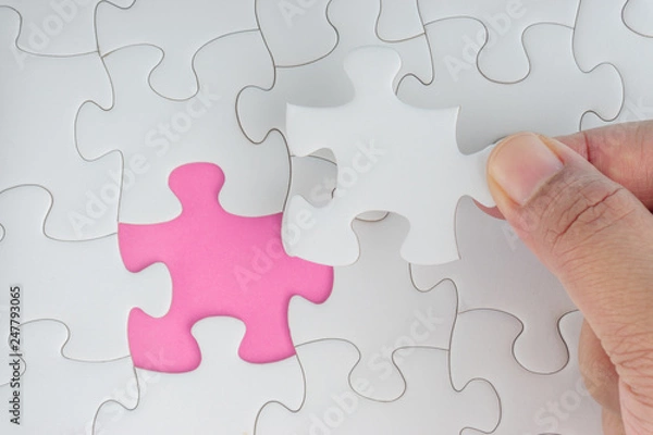 Fototapeta Hand put the last piece of jigsaw puzzle closeup to complete the mission. Selective focus and crop fragment