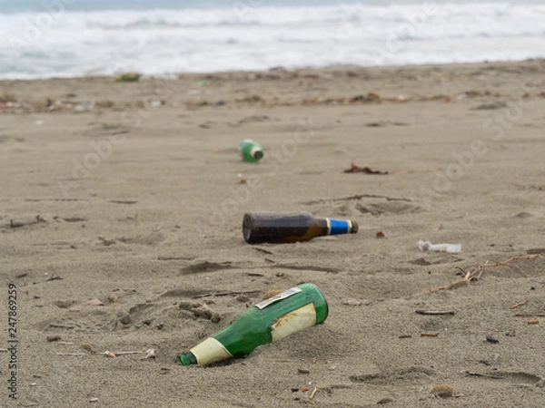 Fototapeta trash on the beach: beer bottles abandoned on the sand