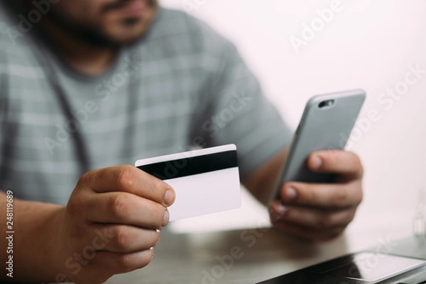 Fototapeta Cropped picture of man with credit card white pattern and phone