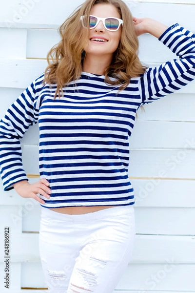 Obraz Уличная фотография молодой брюнетки на белом фоне смотрит в сторону, стоя у деревянного забора. Горизонтальный макет. Пустое пространство для текста o дизайн.