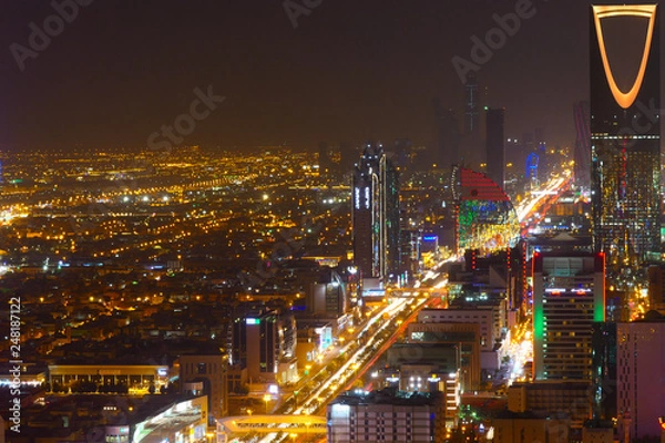 Fototapeta Panorama view to the skyline of Riyadh by night, with the Kingdom centre in the background and yellow lighting, the capital of Saudi Arabia