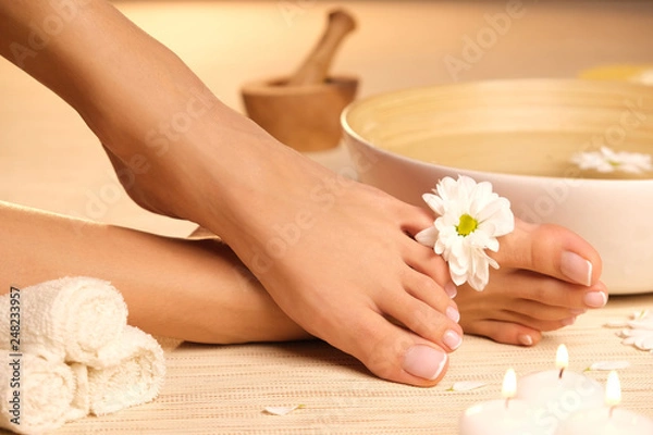 Obraz The picture of ideal done manicure and pedicure. Female hands and legs in the spa spot.