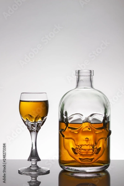 Obraz A skull bottle and crystal glasses with a liquid, alcohol drink.