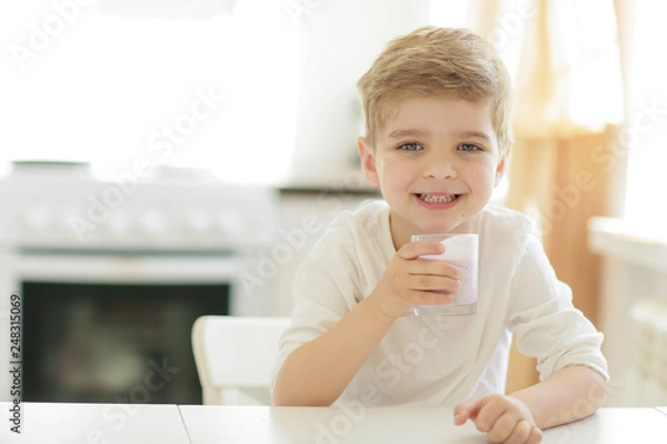 Obraz Kid or blonde happy boy eating at table. Childhood and happiness, independence. Breakfast, morning, family. Small boy child eat banana and drink milk. Healthy food and vitamin. dieting, vegetarian