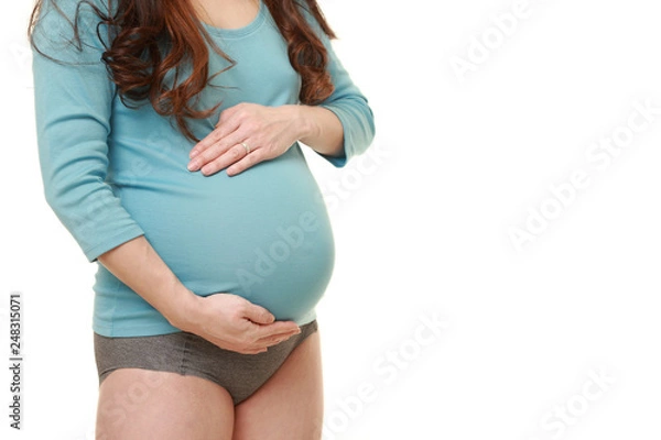 Obraz お腹を触る水色のシャツを着た臨月の妊婦