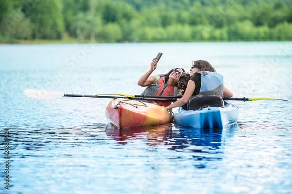 Fototapeta Mother and Daughter Streaming video, facetime, or Taking Selfie with Dog in Kayak while on Vacation