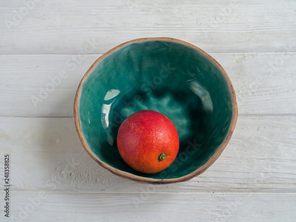 Fototapeta An orange in a bowl on a table