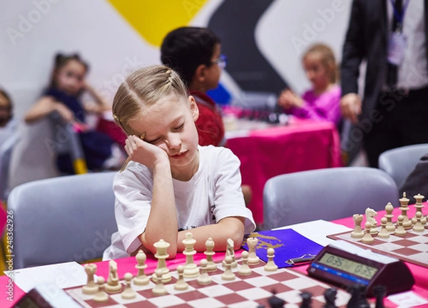 Fototapeta Small cute girl infront of chess board on chess tournament look very bored