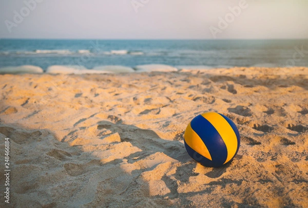 Obraz volleyball dropped on the beach in sunset with open sea and clear sky.
