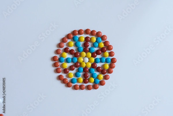 Fototapeta Colorful m m candy laid out in the shape of a floral mosaic isolated on white background. Decorative arnament