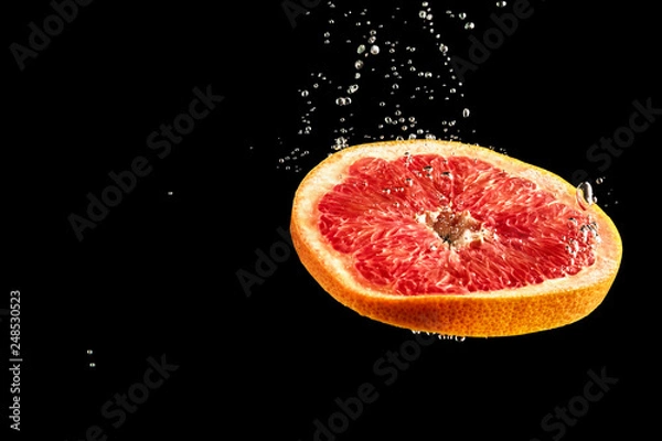 Fototapeta Grapefruit dropped into the water surrounded by bubbles