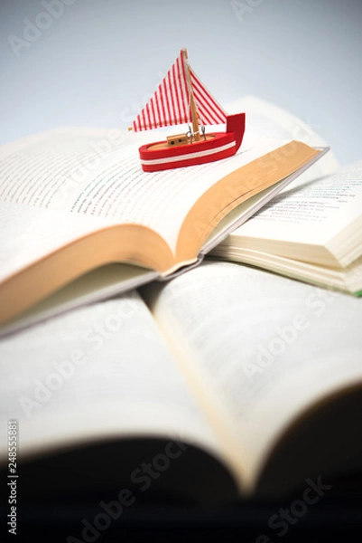 Obraz boat navigating between books, traveling, reading, adventures in books