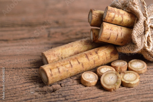 Obraz fresh burdock root or Gobo in sack and on wooden background