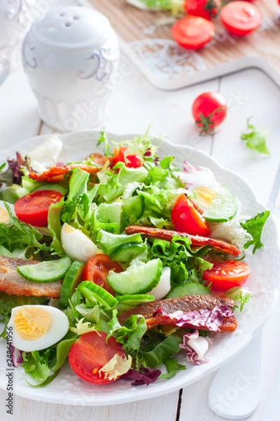 Fototapeta fresh salad of roasted bacon, tomatoes and eggs on a white plate, selective focus